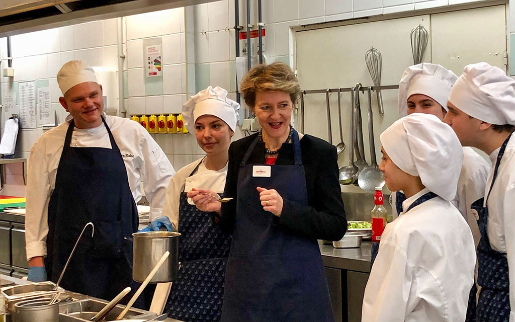 La consigliera federale Simonetta Sommaruga in una cucina con futuri cuochi e cuoche che svolgono una formazione professionale secondo il modello svizzero.