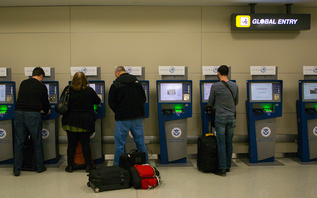 Des voyageurs se tiennent devant des bornes automatiques du programme Global Entry dans un aéroport international