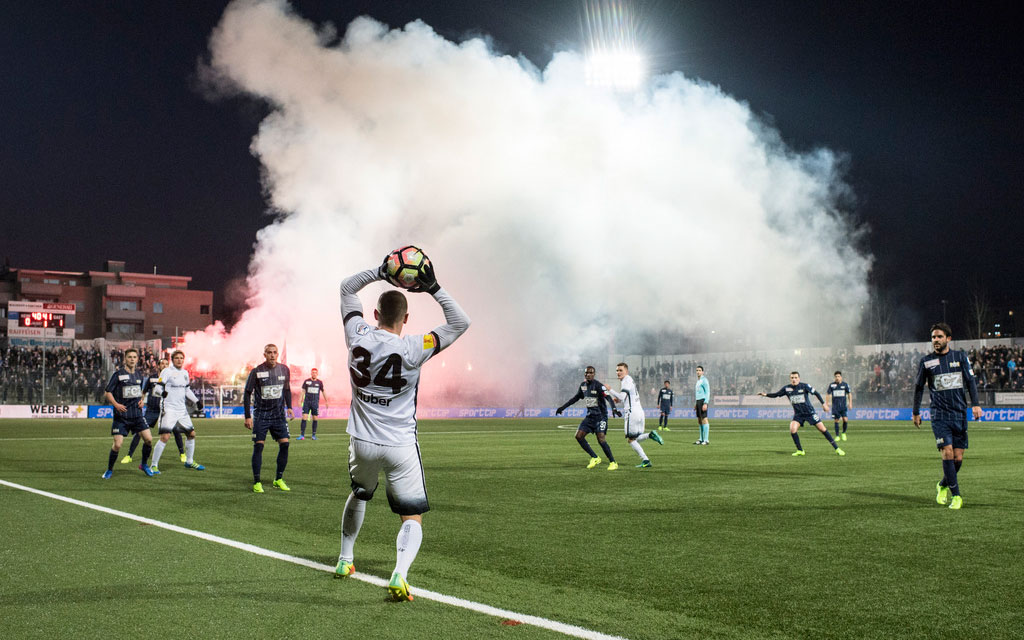 Des supporters allument des engins pyrotechniques pendant un match de football.